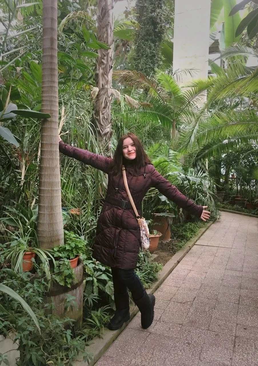 A portrait of me surrounded by lush greenery and vibrant flowers in a botanical garden.